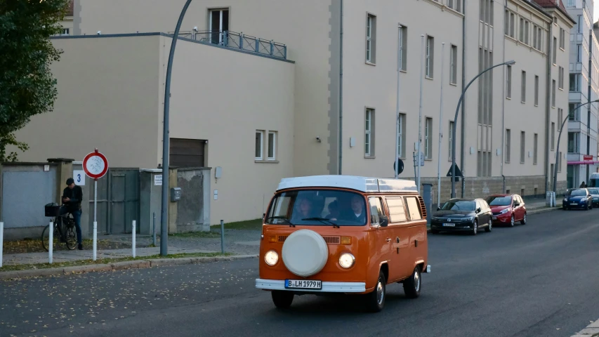 the small orange van is driving down the street