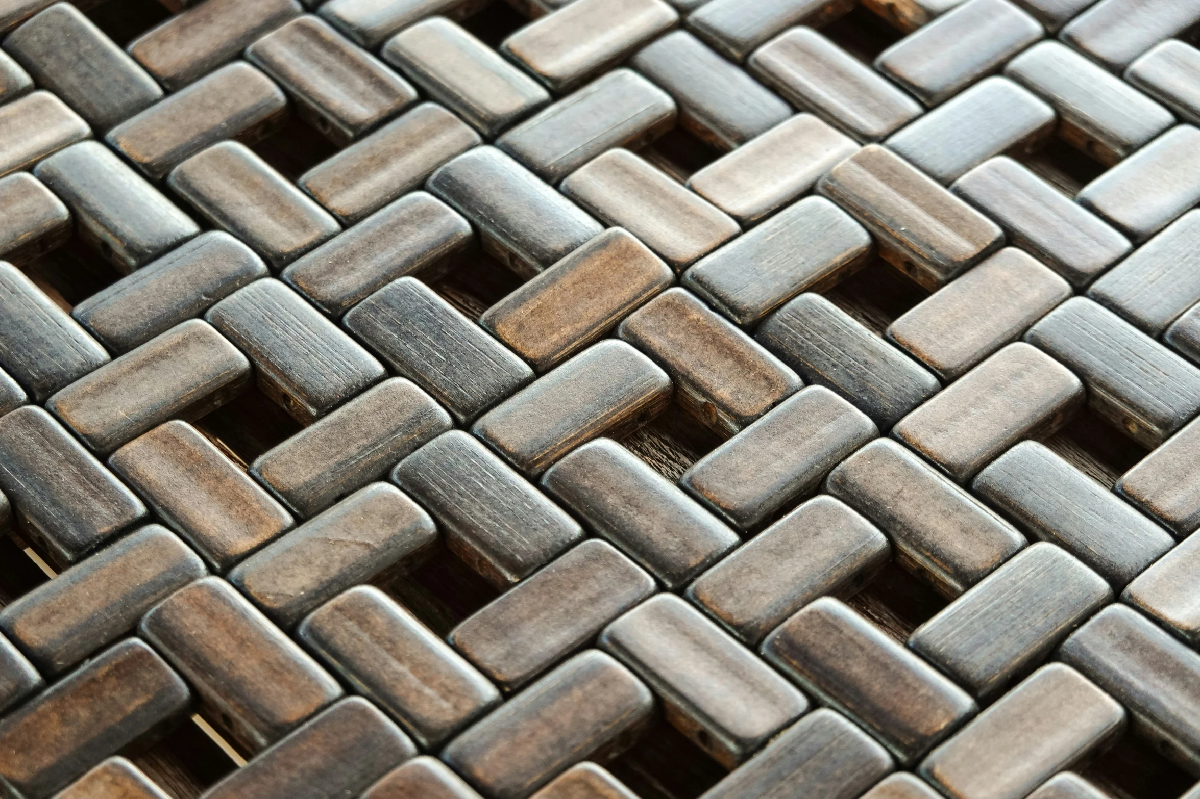 the woven surface of a mosaic tile has brown, silver and black