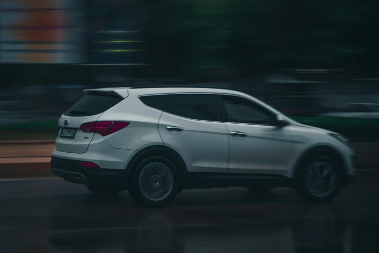 a white vehicle driving down the road at night