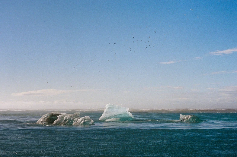 a small iceberg floats off of the water with another in the background