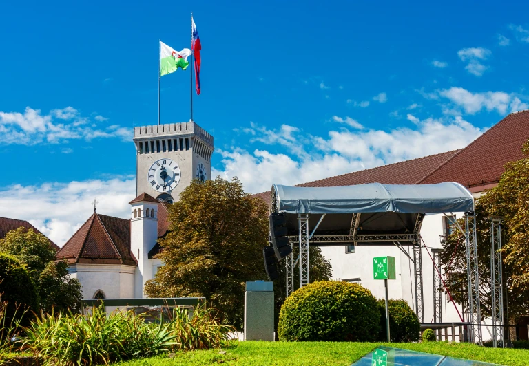 an area with bushes, flowers and a large tower with a clock on it