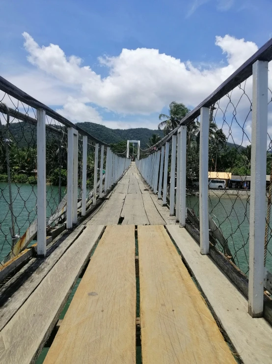 a long wooden bridge over water with white railings