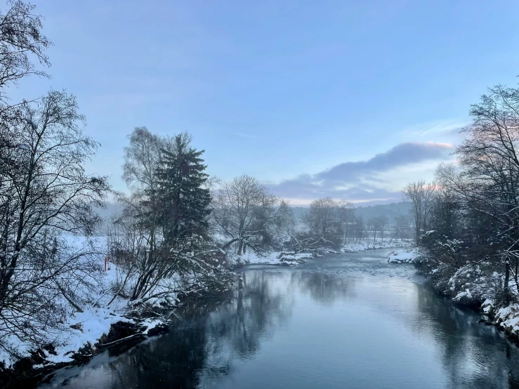 a view of the snowy countryside, showing the water and trees