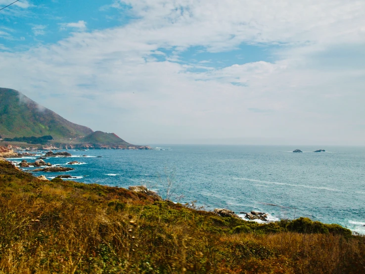 people are walking along the edge of a cliff overlooking an ocean