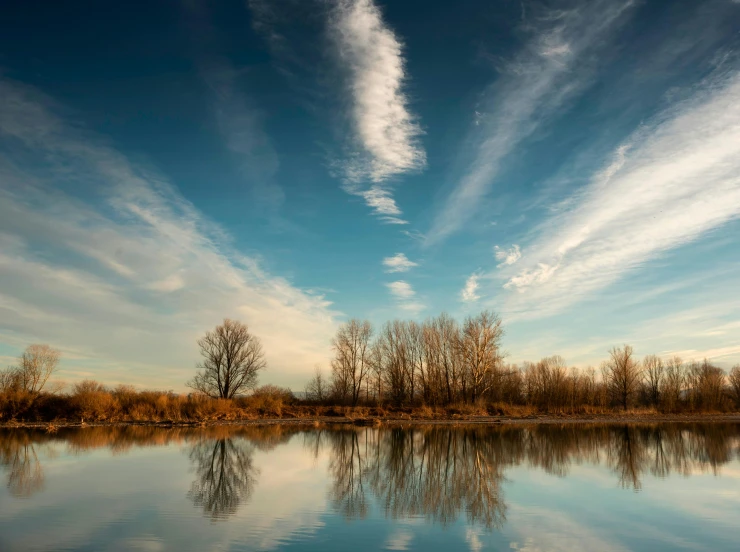 the sky above a body of water with trees in the background