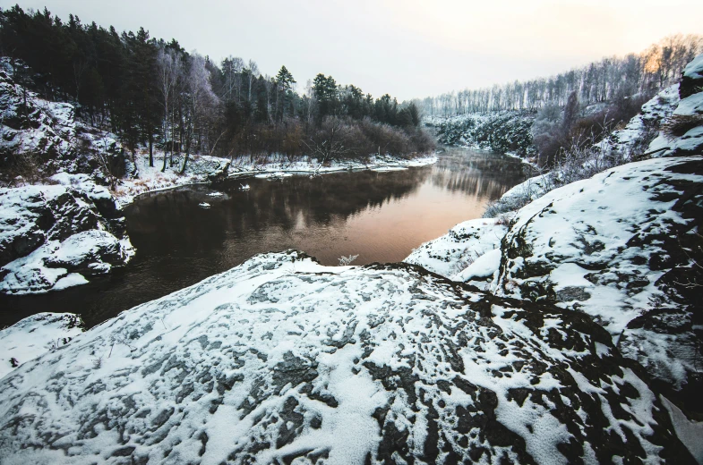 a river with some snow and trees in the background