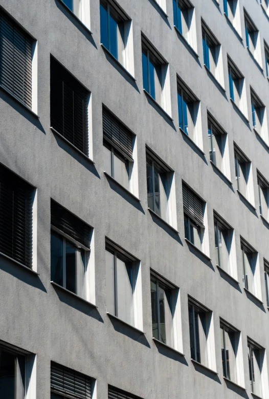 grey building with large windows and closed shutters