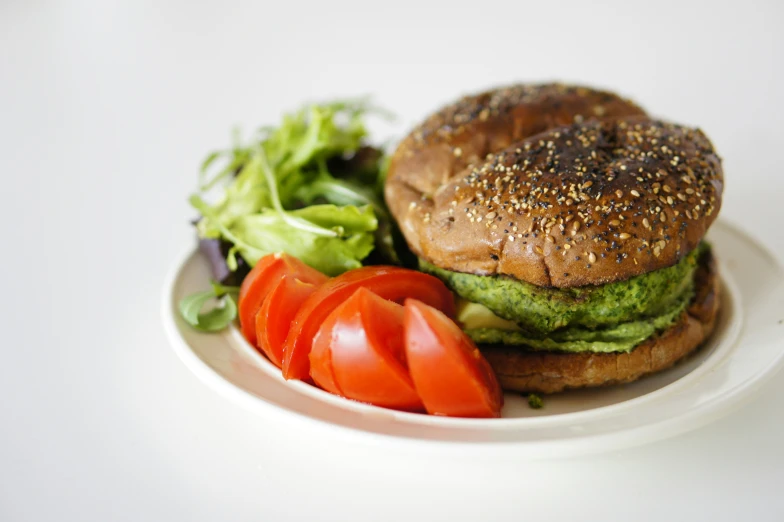 a bagel on a white plate and some salad