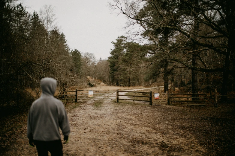 the person in the hooded jacket is walking toward a gate