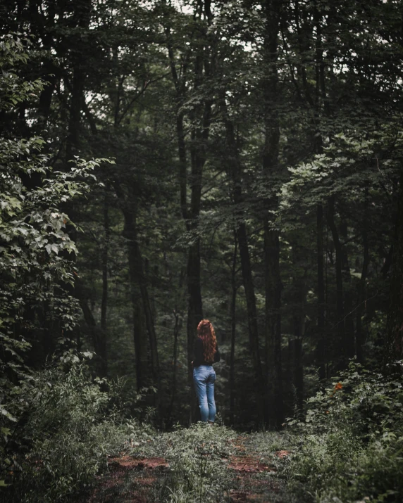 a person standing in the woods with a jacket on