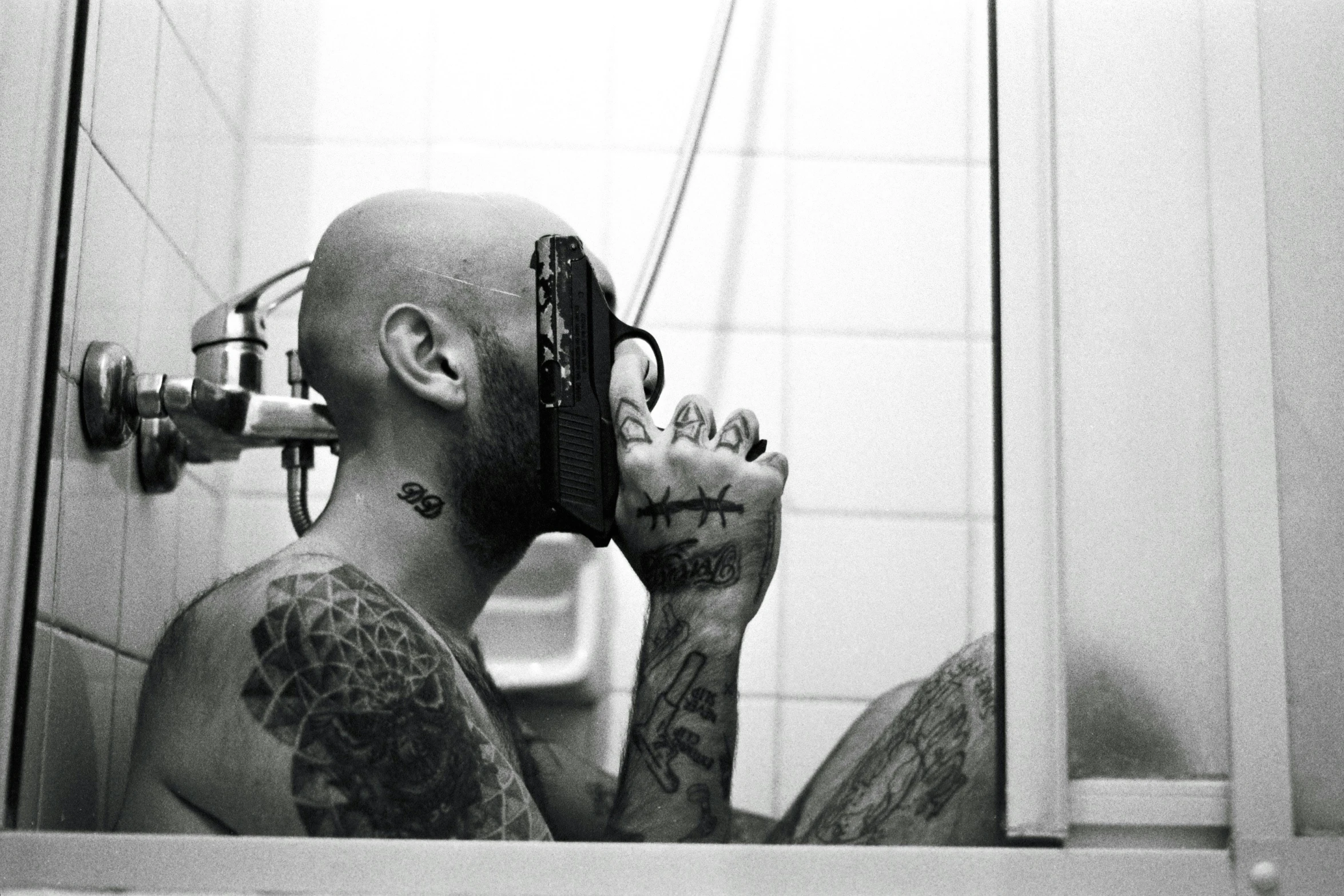 the reflection of a tattooed man with a knife in a mirror