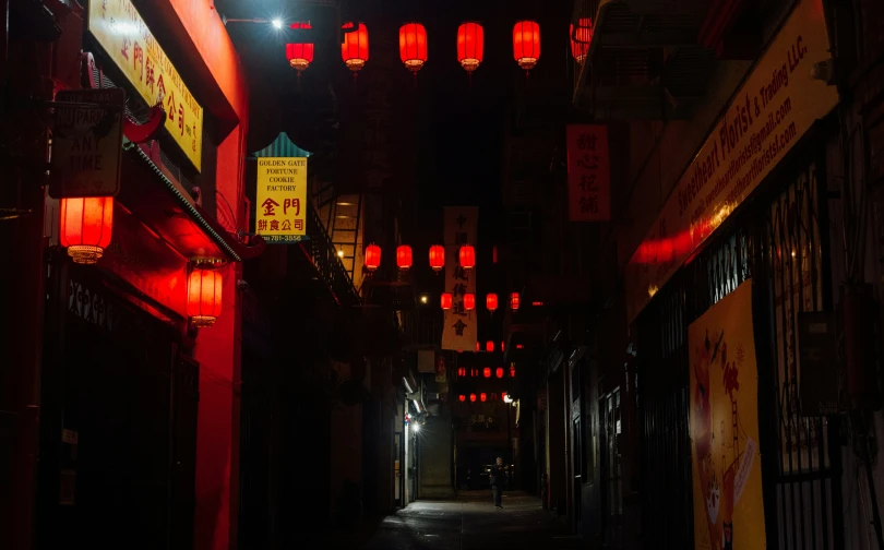a dark alley in an asian town has red lanterns on the ceiling and lights above