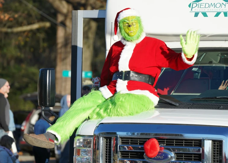 a man dressed as santa claus rides on top of a pickup truck