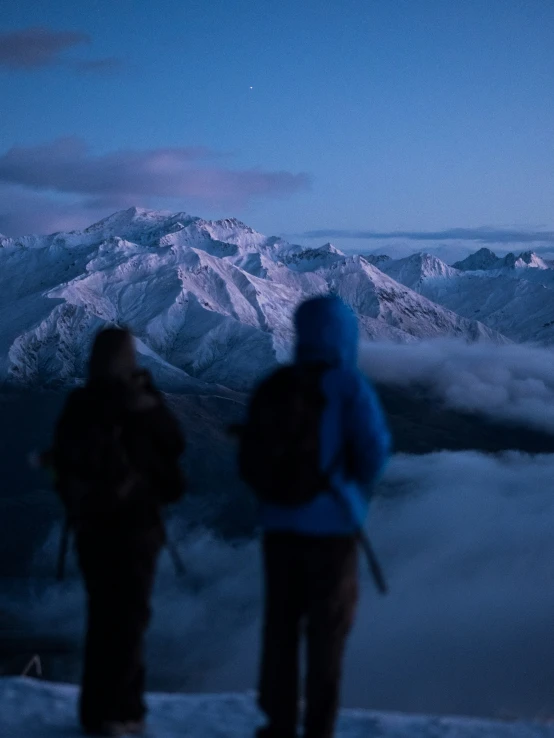 two people standing in the snow with their backpacks on