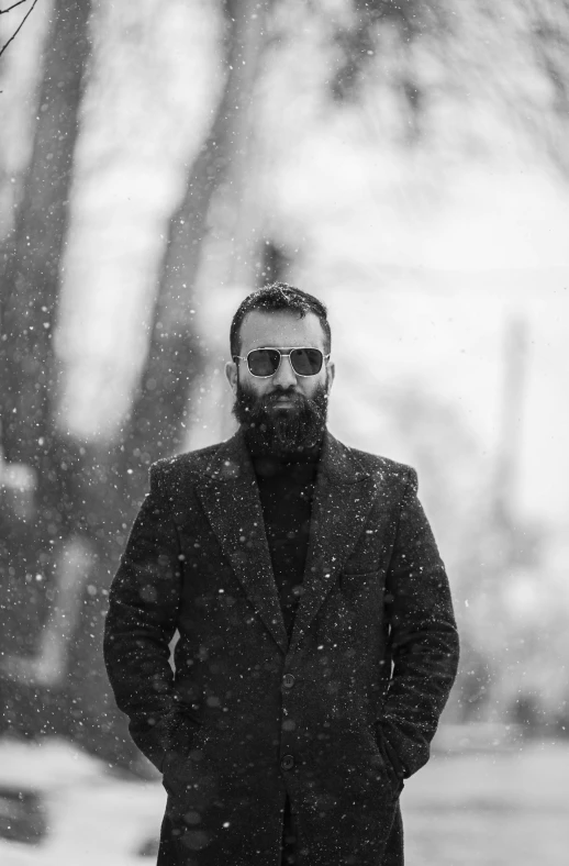 a man wearing glasses standing in the snow