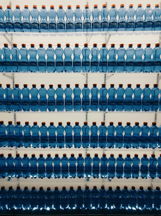 blue water is stacked in the front and back of two shelves