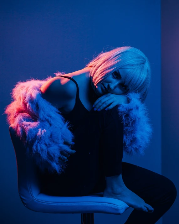 a woman with a long, white hair sitting in a chair with her face propped up against her knees