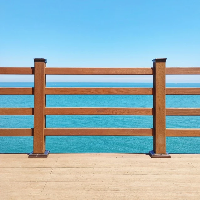 a large wooden fence by the ocean against a blue sky