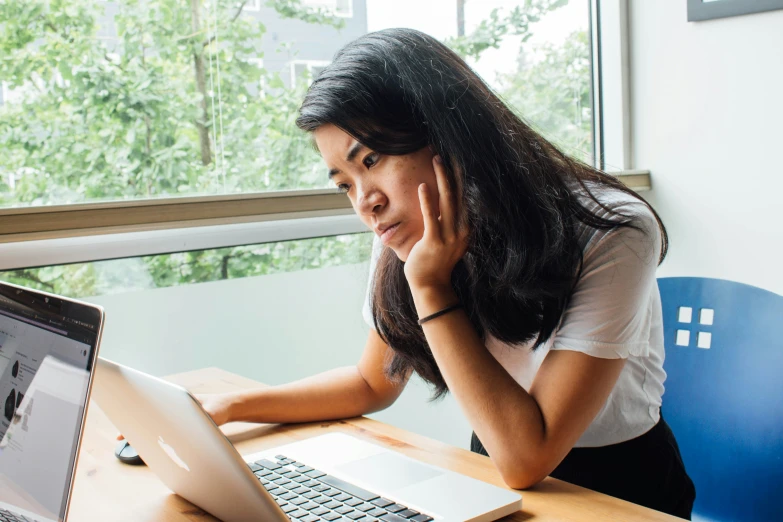 a woman is sitting at a desk in front of a laptop