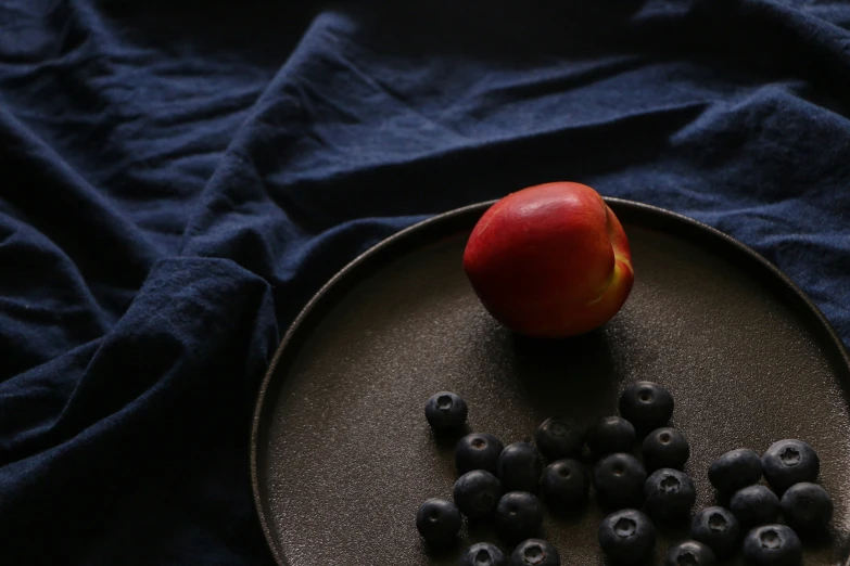 an apple on top of blueberries in a plate