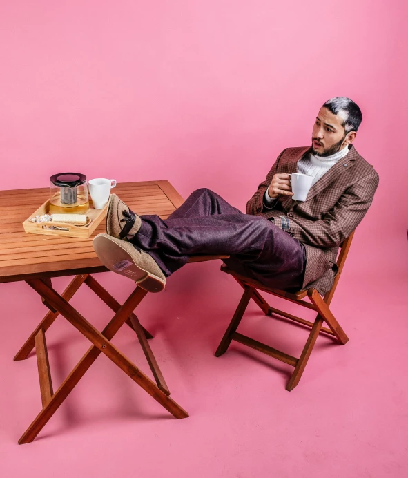 a man is sitting at a table with a cup of coffee