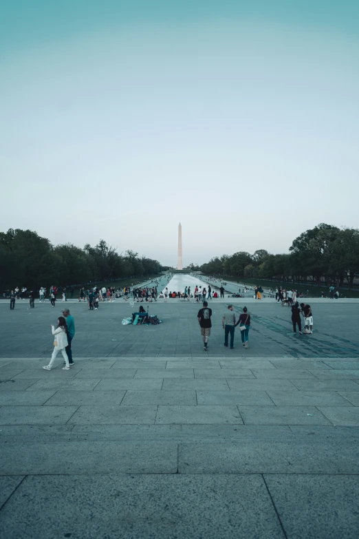 some people walking around an area that has statues on it