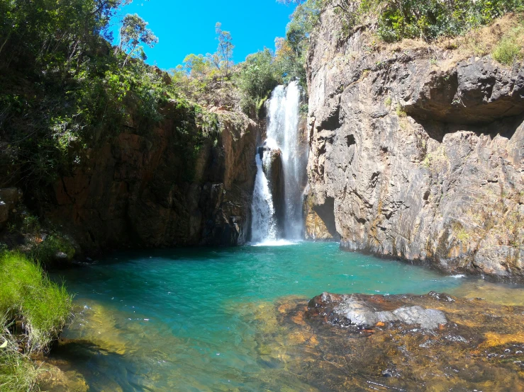 a waterfall surrounded by cliffs and blue water