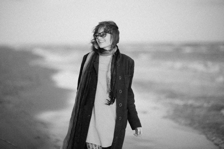 a woman wearing glasses standing on a beach