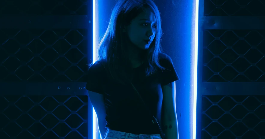 a woman standing in front of blue neon lights