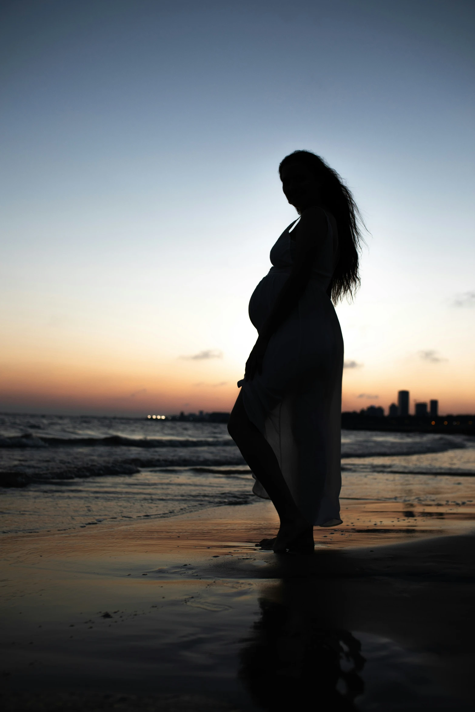 pregnant woman at the beach in silhouette against the sunset