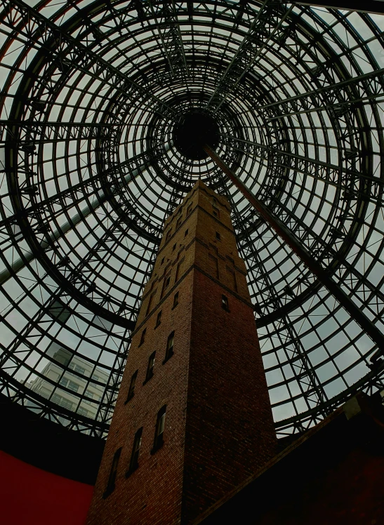 looking up at the glass roof and the clock tower of a brick building