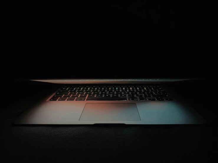 a lit up laptop computer on a black surface