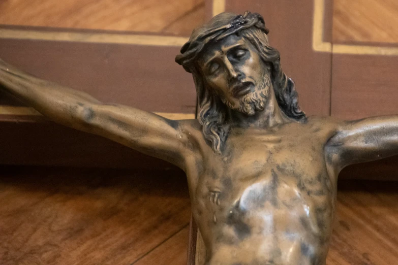 statue of jesus on the cross with a wood background