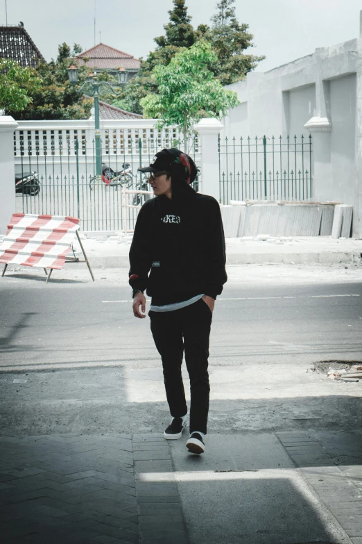 young man walking alone along the pavement in the day