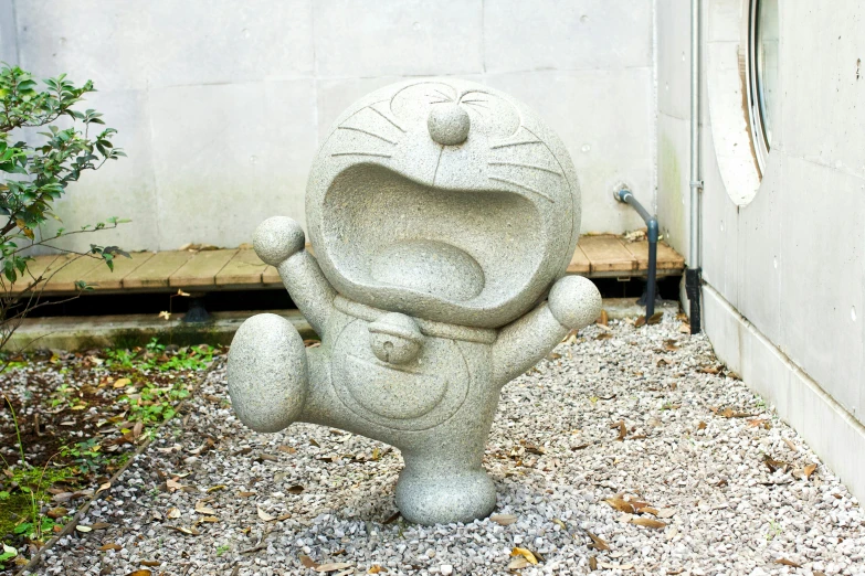 stone sculpture with an expression of emotion sitting in front of cement wall