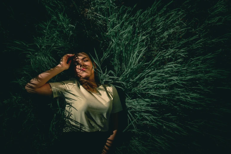 a woman is walking through green grass at night