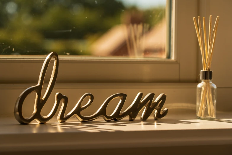 the word dream sits near a window near a reed diffuser