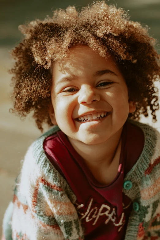 a little girl smiling for a po with curly hair