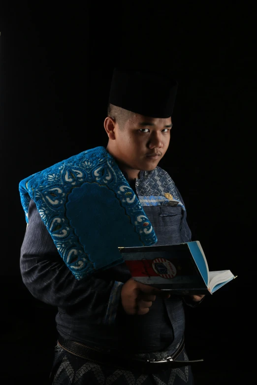 a man wearing a shawl holding a blue book