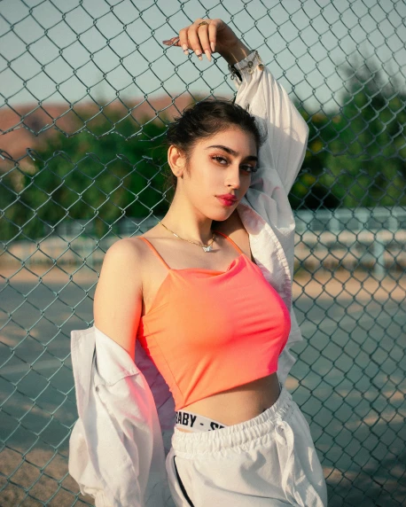 a woman posing next to a fence in her neon top