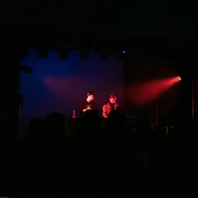 two people on stage at night with lights on