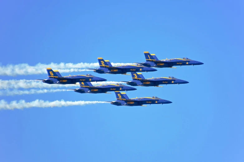 four blue angels jet airplanes with smoke trailing behind