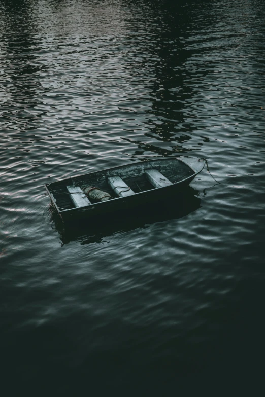 a black boat on water with trees in background