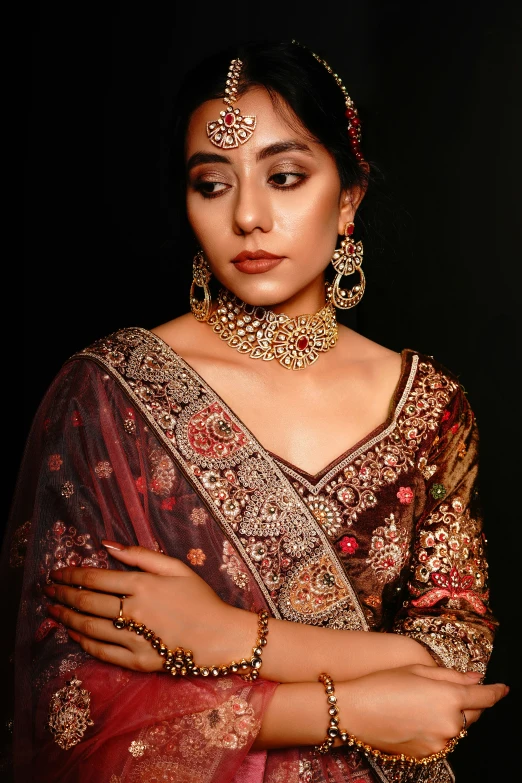 a woman wearing an orange, gold and red saree with large jewelry