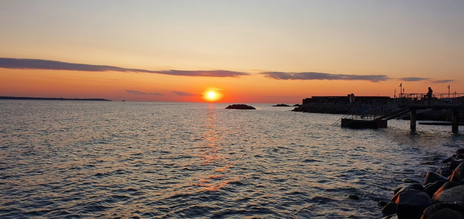 a small boat out at sea during sunset