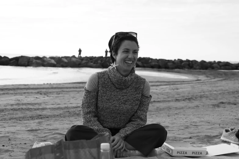 a woman sitting on a beach with the ocean in the background