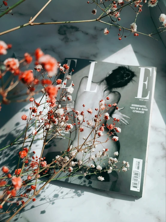 a close up view of a magazine with flowers near it