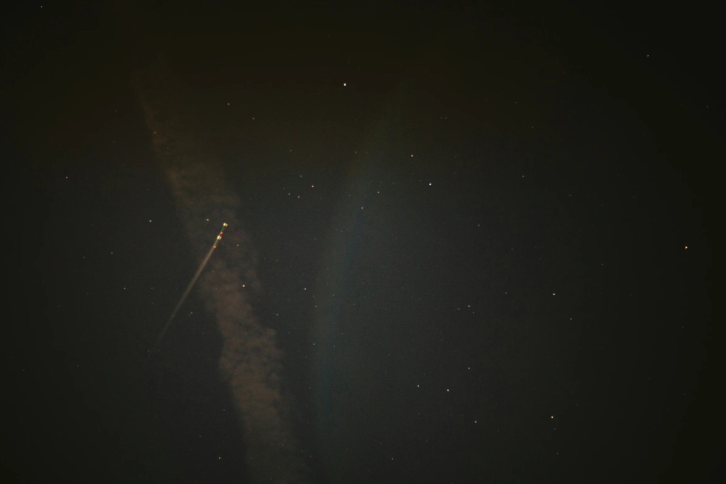 a very dark sky and a plane flying through it