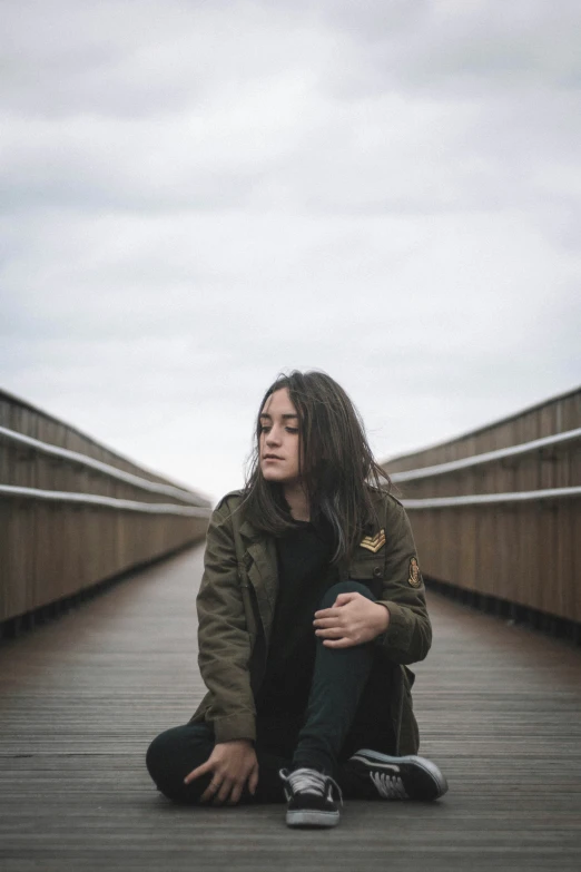 a woman sits on a wooden bridge with her legs crossed