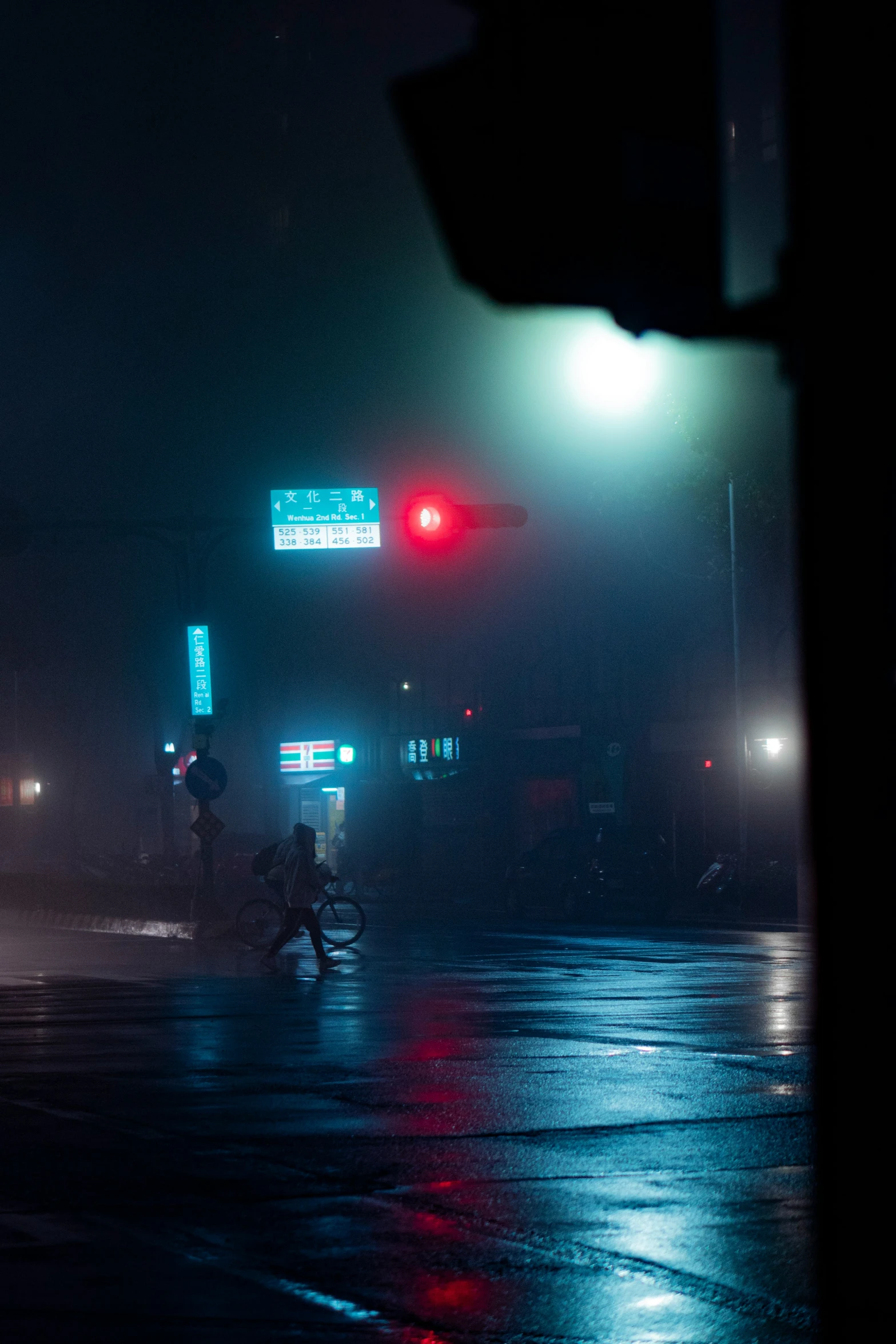 a street filled with traffic at night with light posts in the fog